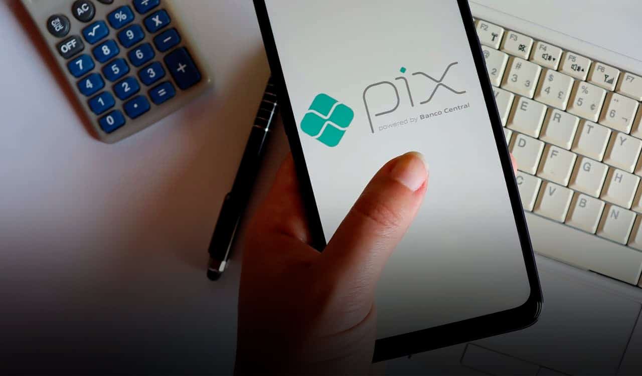 Imagem de uma mão segurando um celular com a tela no PIX