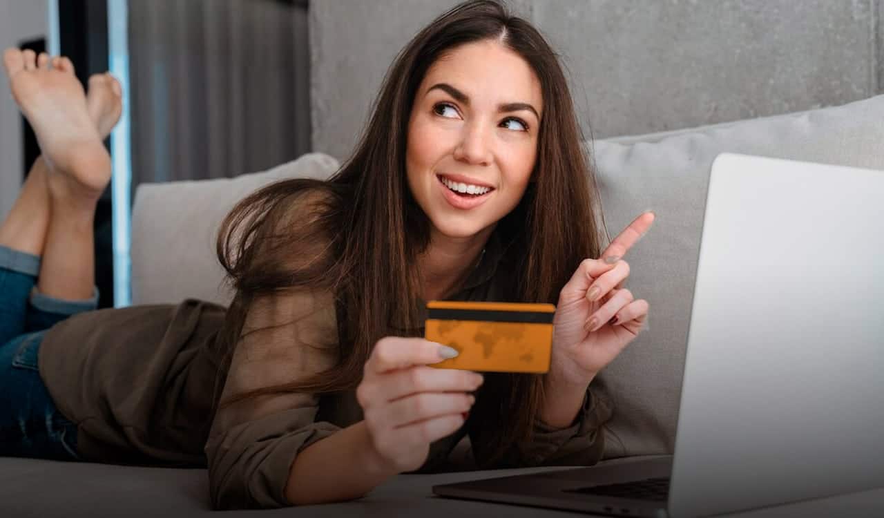 Mulher deitada com um cartão de crédito do Itaú na mão
