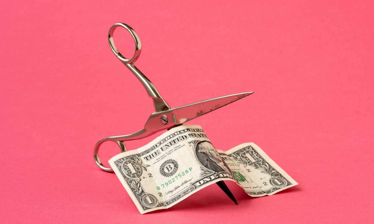Tesoura cortanto uma nota de dólar