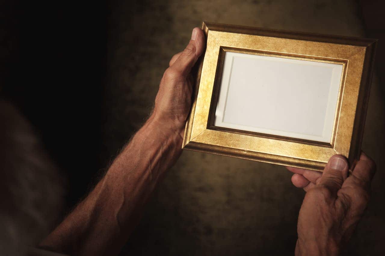 Braços de pessoa idosa segurando porta retrato sem foto