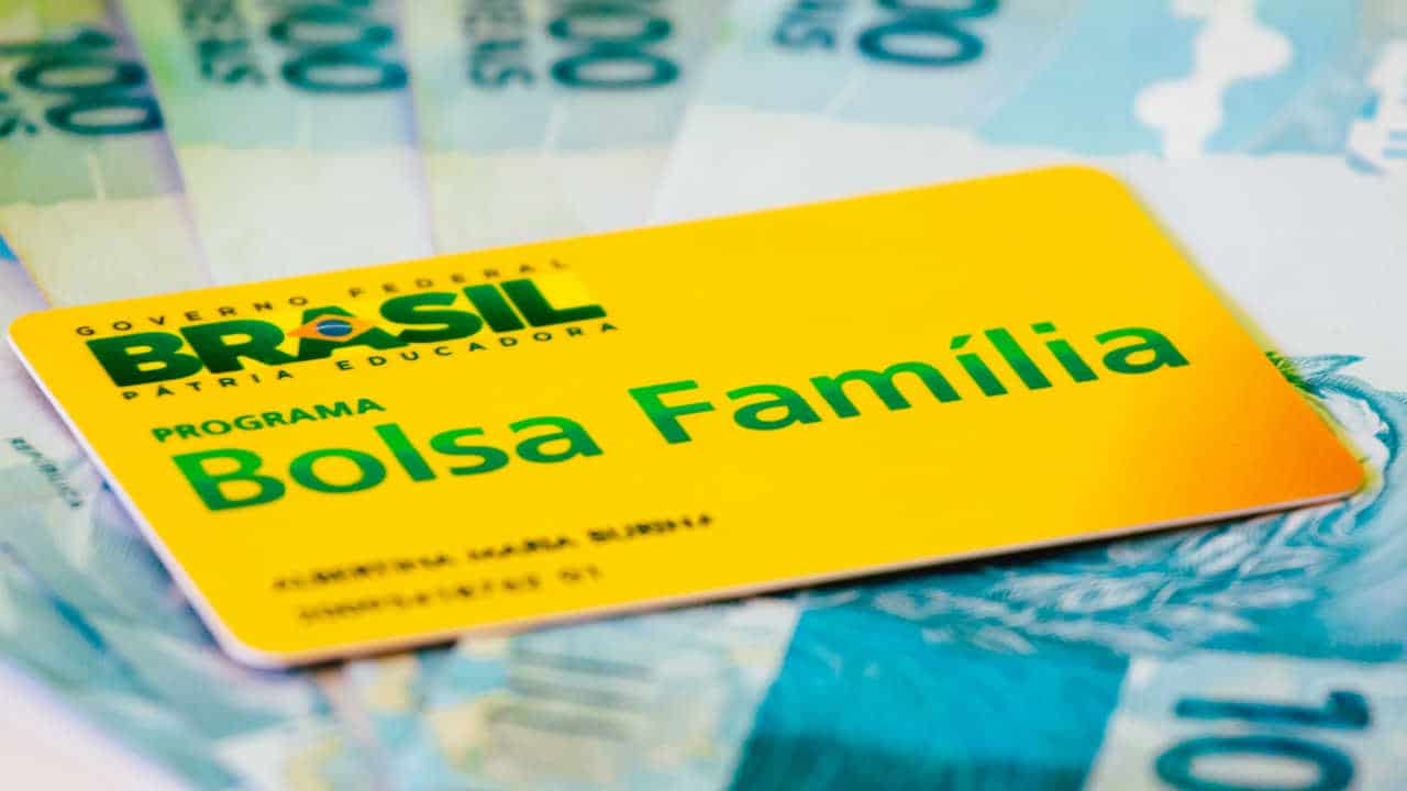 Cartão do Bolsa Família por cima de notas de 100 reais
