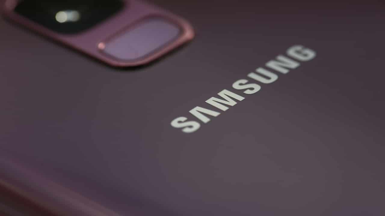 Visão aproximada da parte traseira de um celular da Samsung, mostrando em detalhe uma parte da câmera e o logotipo da marca.