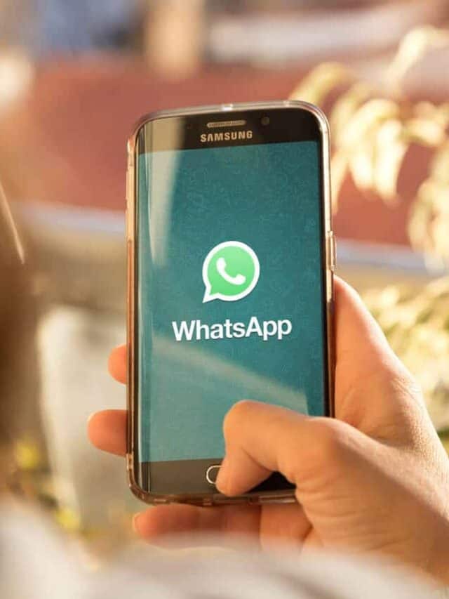 Mulher segurando um celular com o aplicativo do WhatsApp aberto na tela inicial