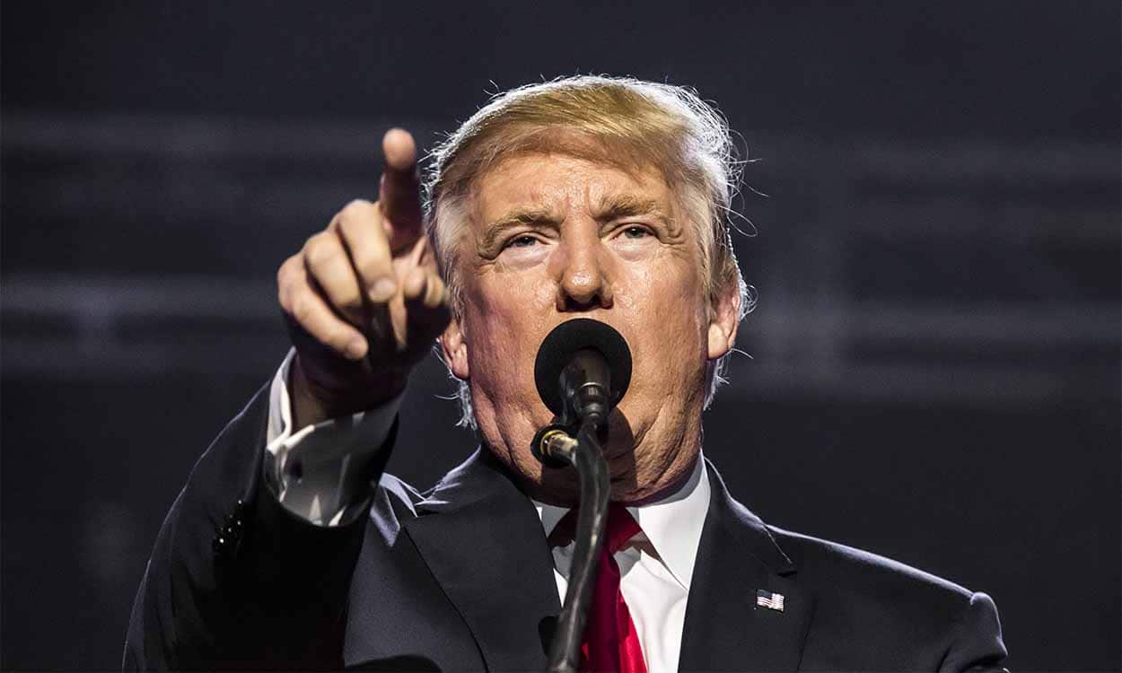 Donald Trump apontando com dedo indicador enquanto fala ao microfone