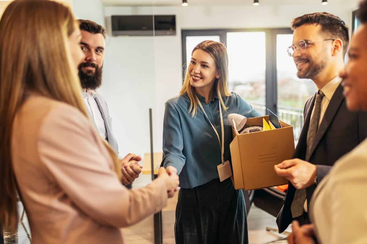 Mulheres apertando as mãos com os colegas de trabalho ao redor.