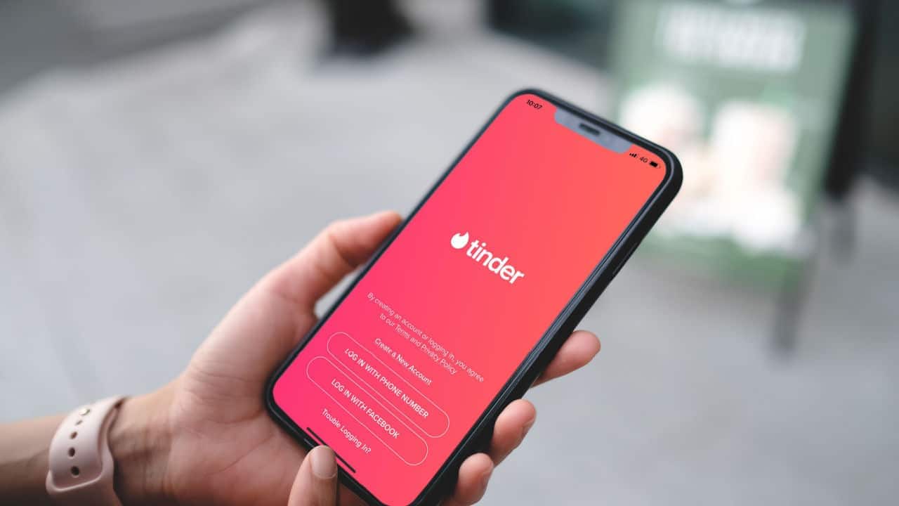 Mão segurando celular exibindo aplicativo do tinder