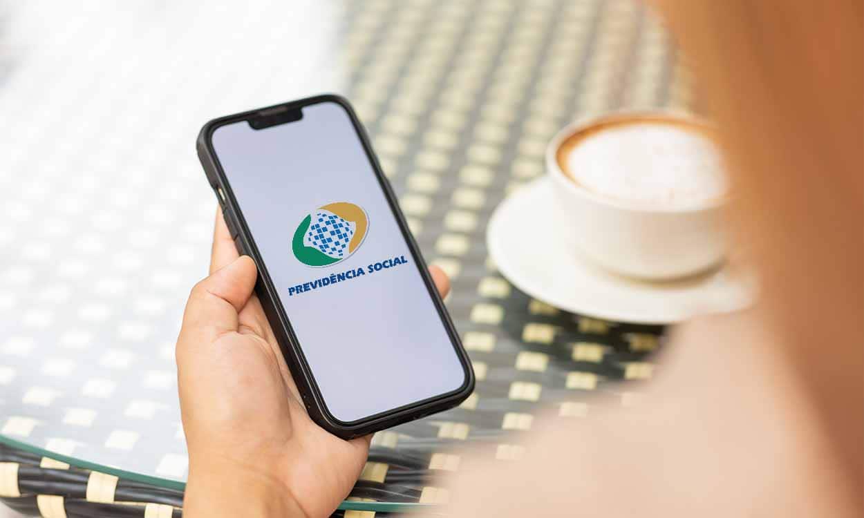 Mão segurando celular aberto no INSS