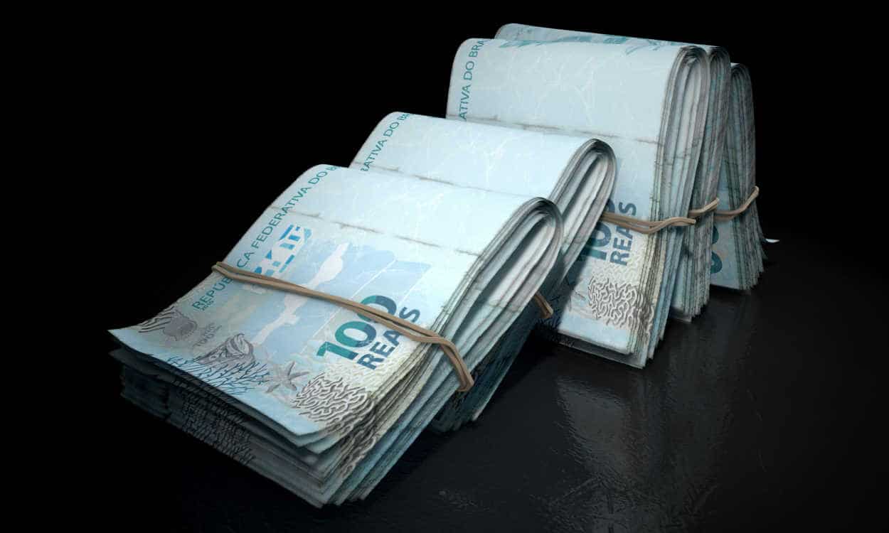 Conjuntos de notas de R$ 100 presas com elástico e apoiadas um nos outros