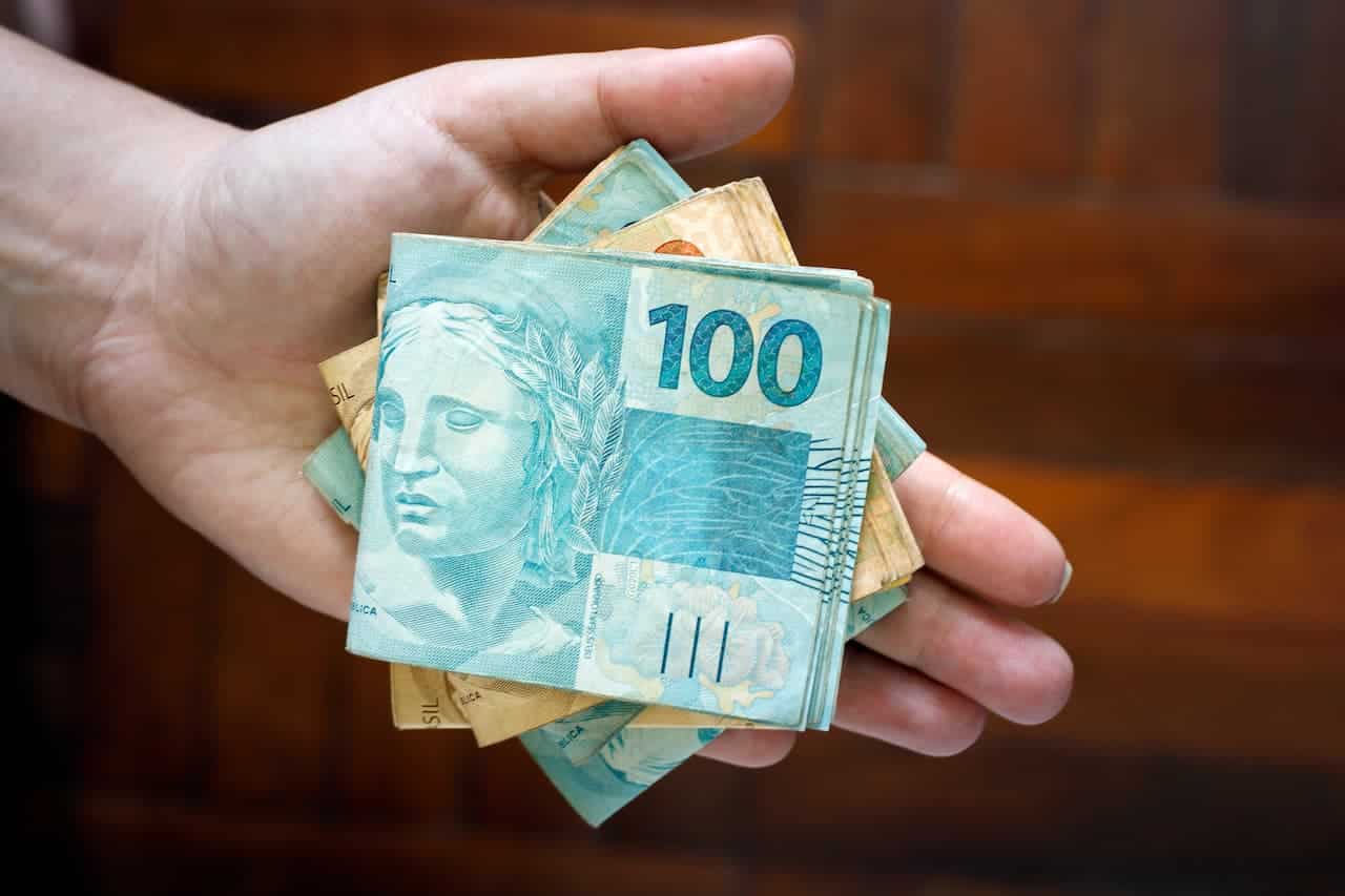 Notas de cem reais e vinte reais em mão