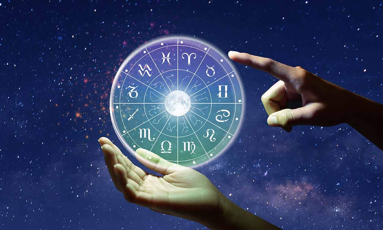 Uma mão segurando uma esfera de luz com os doze signos do zodíaco, enquanto outra aponta o dedo indicador para algum.