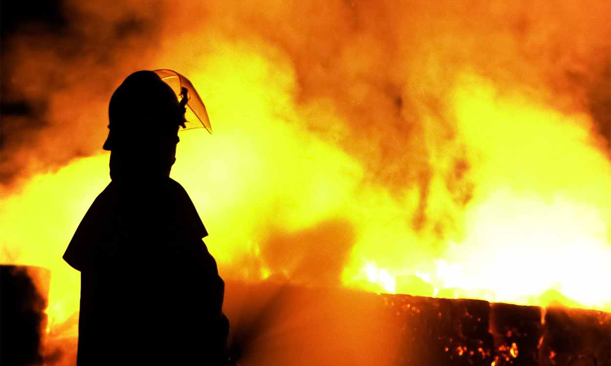 chamas vermelhas de incêndio e a silhueta de um bombeiro