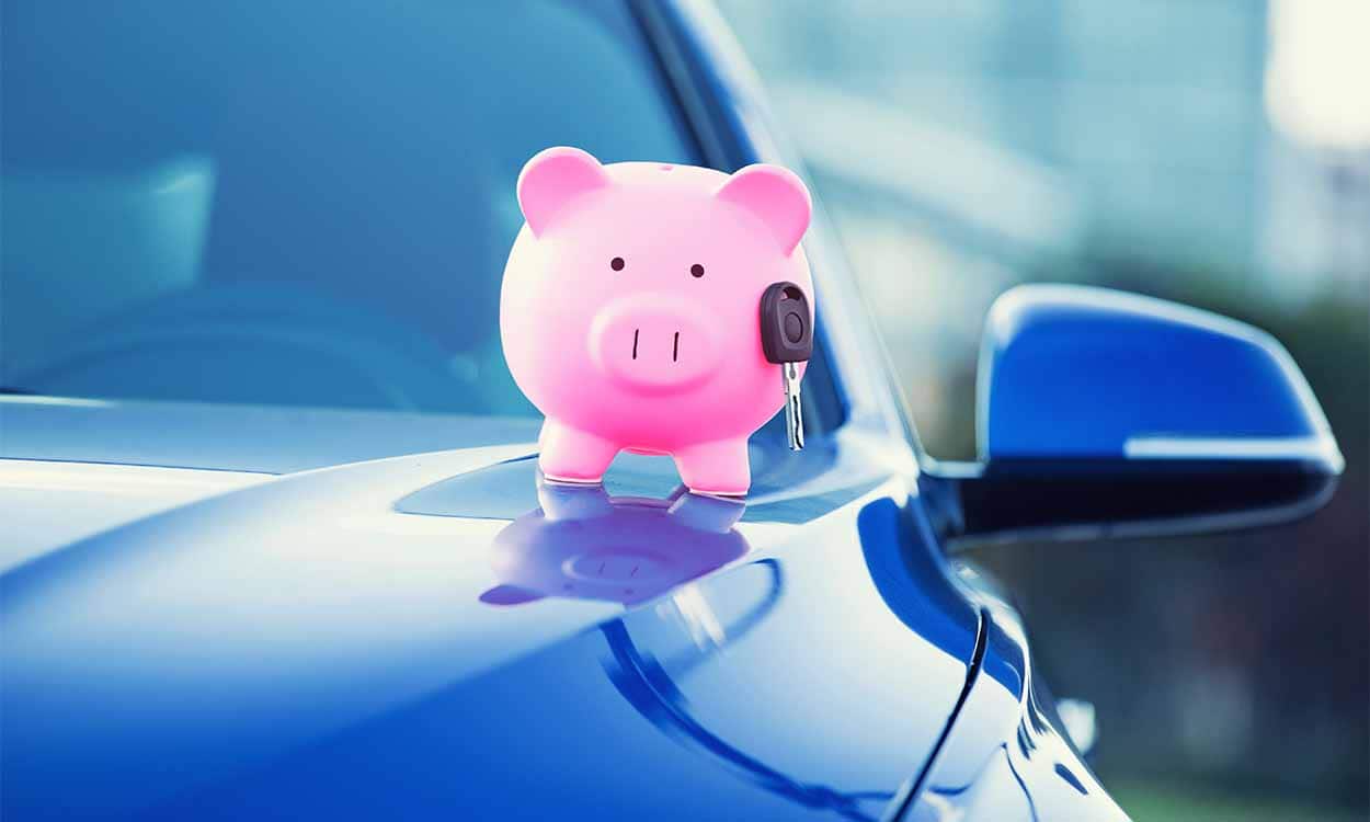 Pequeno cofrinho em formato de porco em cima do capô de um carro