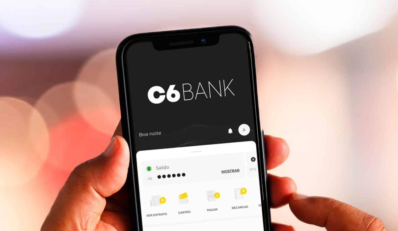 Mão segurando smartphone com o aplicativo do C6 Bank aberto