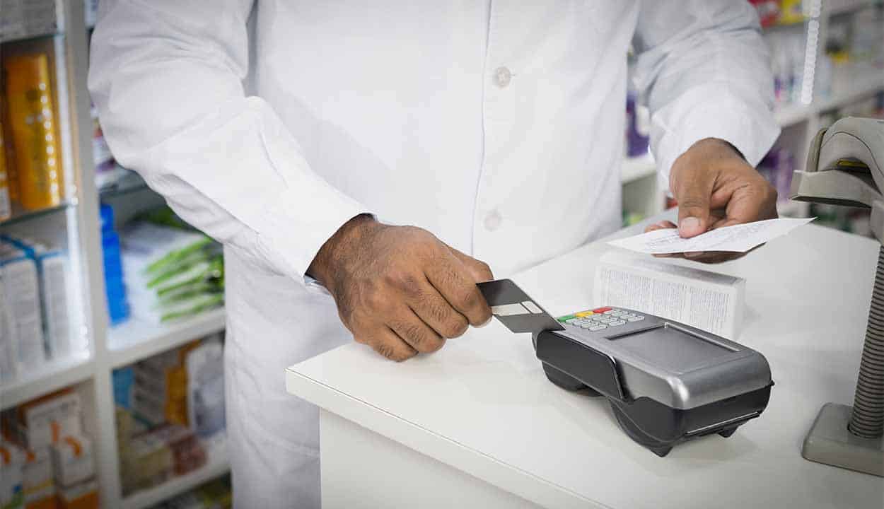 Homem passando cartão em maquininha na farmácia
