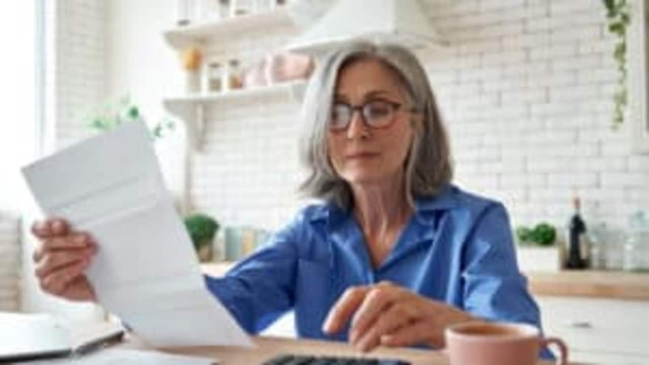 mulher idosa lendo papel em sua mão