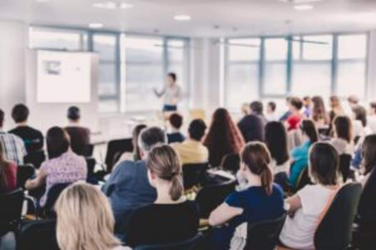 Aula de universidade com diversos alunos e alunas