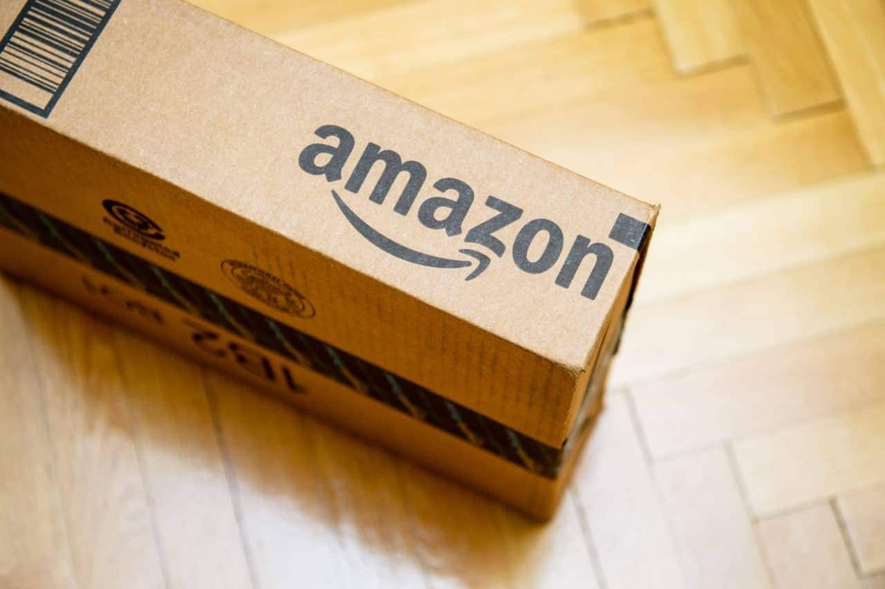 Caixa de papelão no chão e com o emblema da loja Amazon.