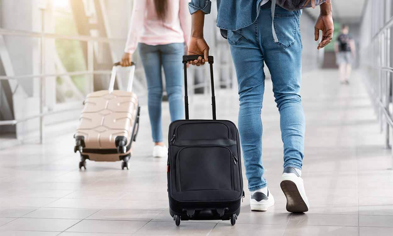 Pessoas puxando malas de mão em aeroporto