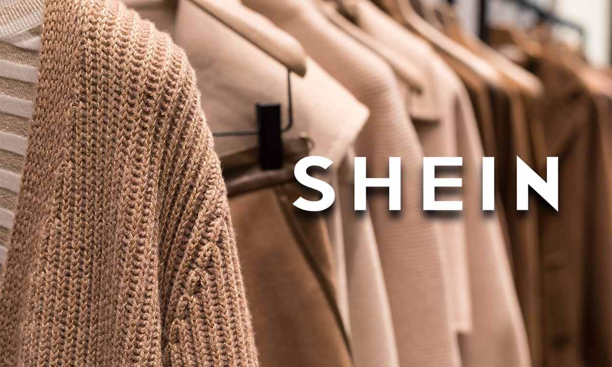 Logo da Shein no lado direito, ao fundo estão cabides de casacos em uma loja de roupas.
