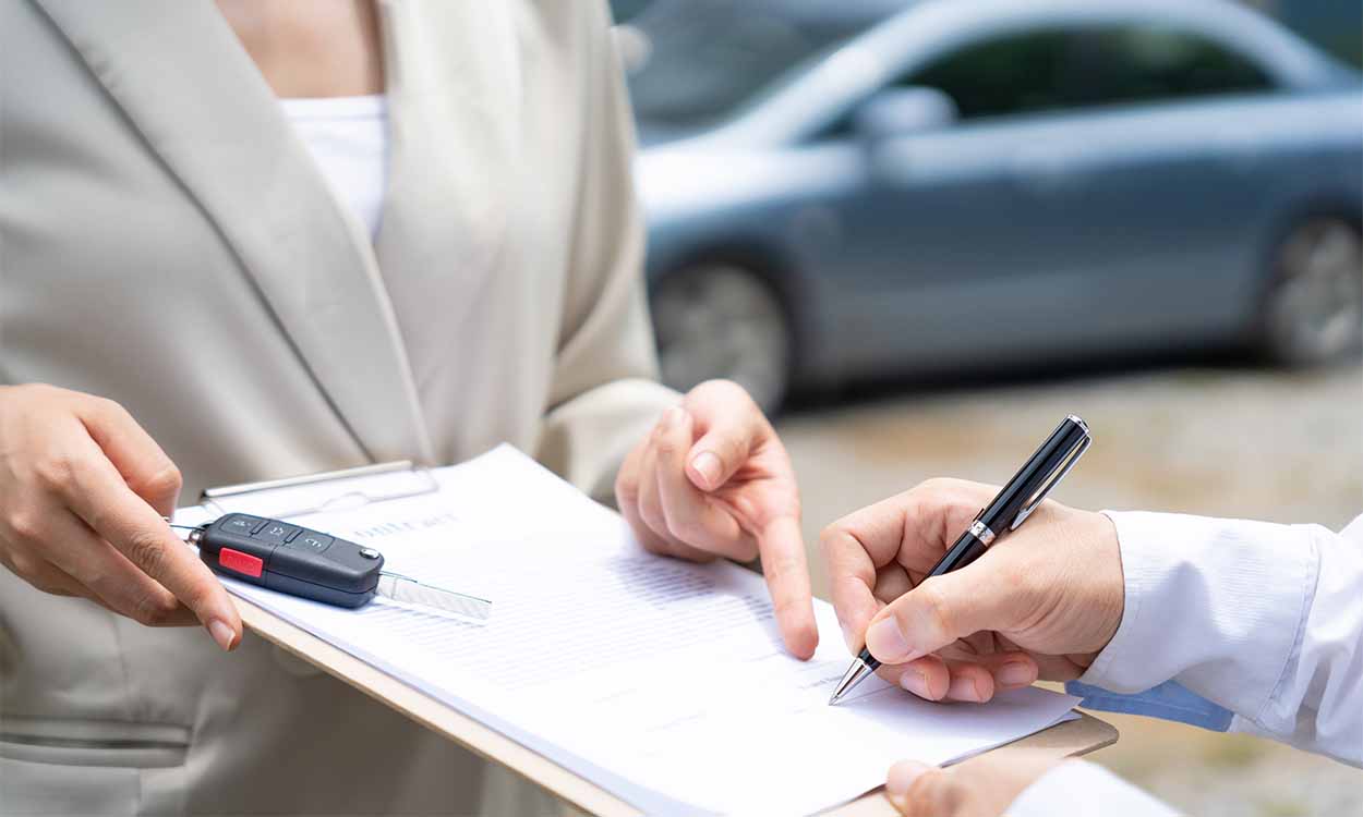 Cliente assinando documentação de carro e recebendo chave