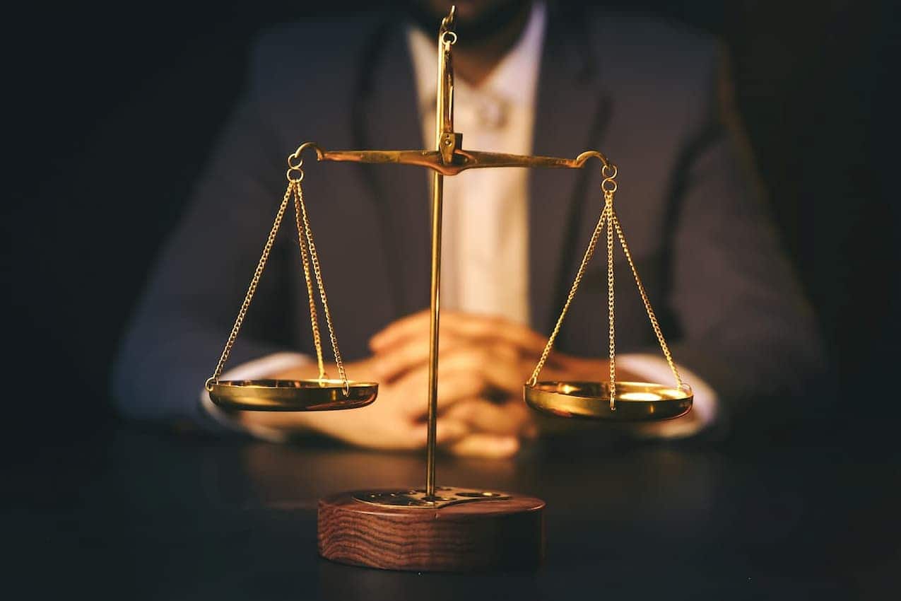 balança equilibrada e homem engravatado ao fundo