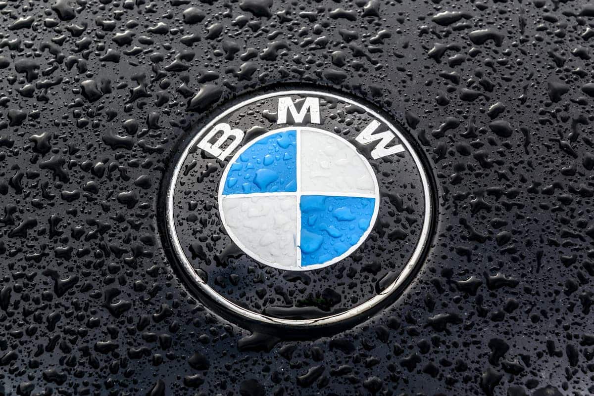 Logotipo BMW sobre capô preto com gotículas de água. multa