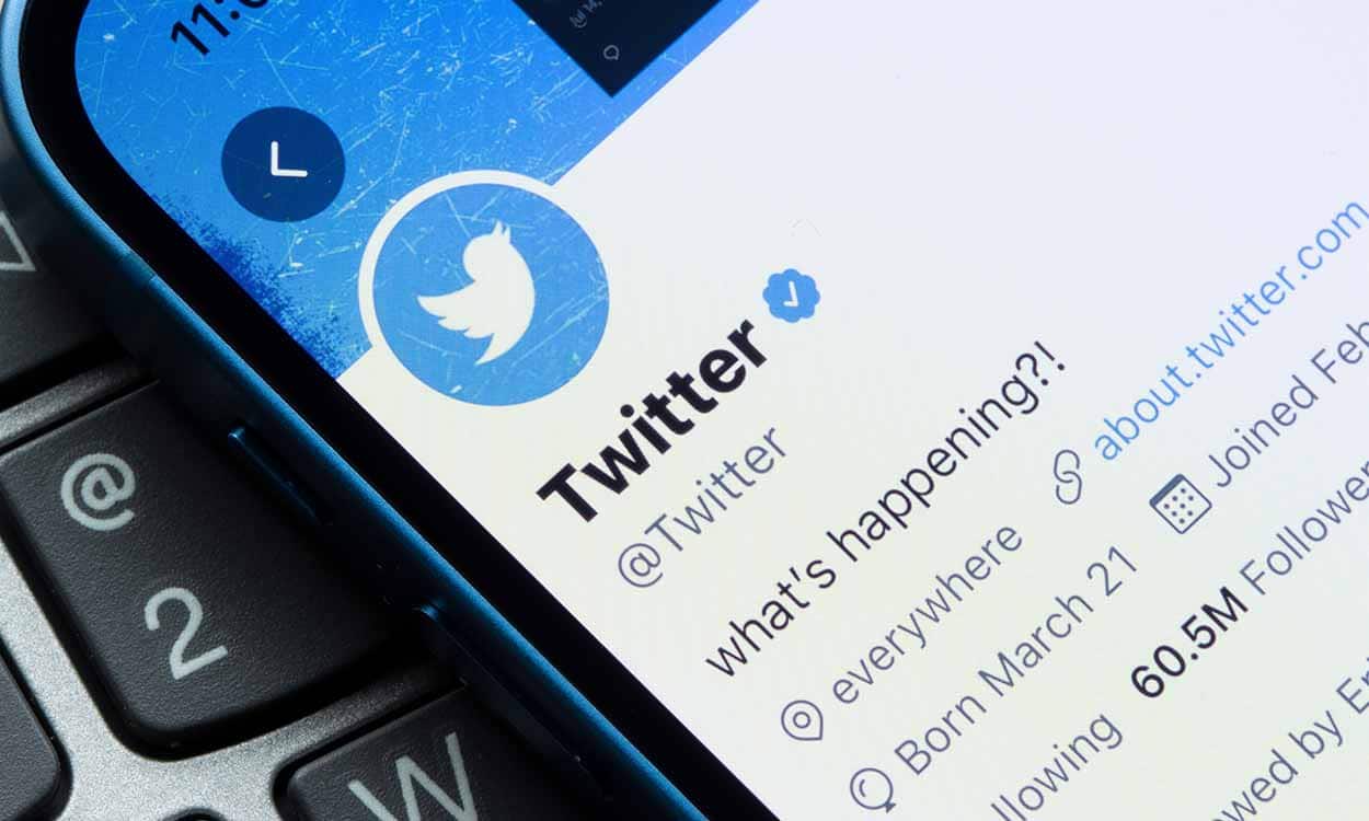 celular com aplicativo do Twitter aberto, em cima de um teclado de computador ou notebook