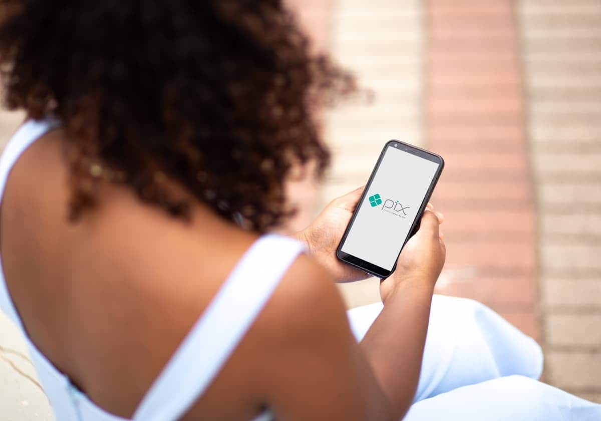 Cliente utilizando Pix através de celular em sua mão