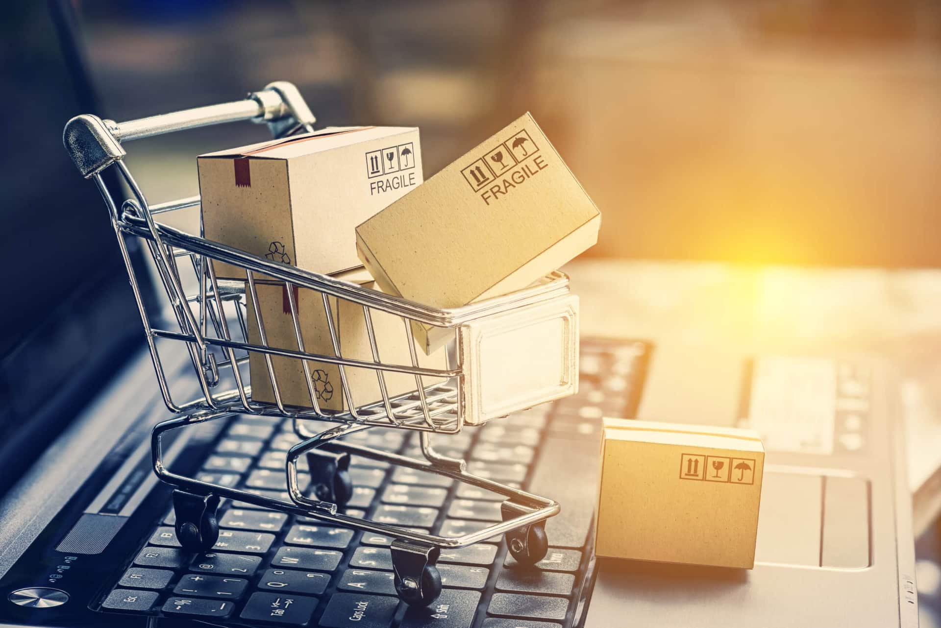 miniatura de carrinhos de compras com caixas em cima de laptop