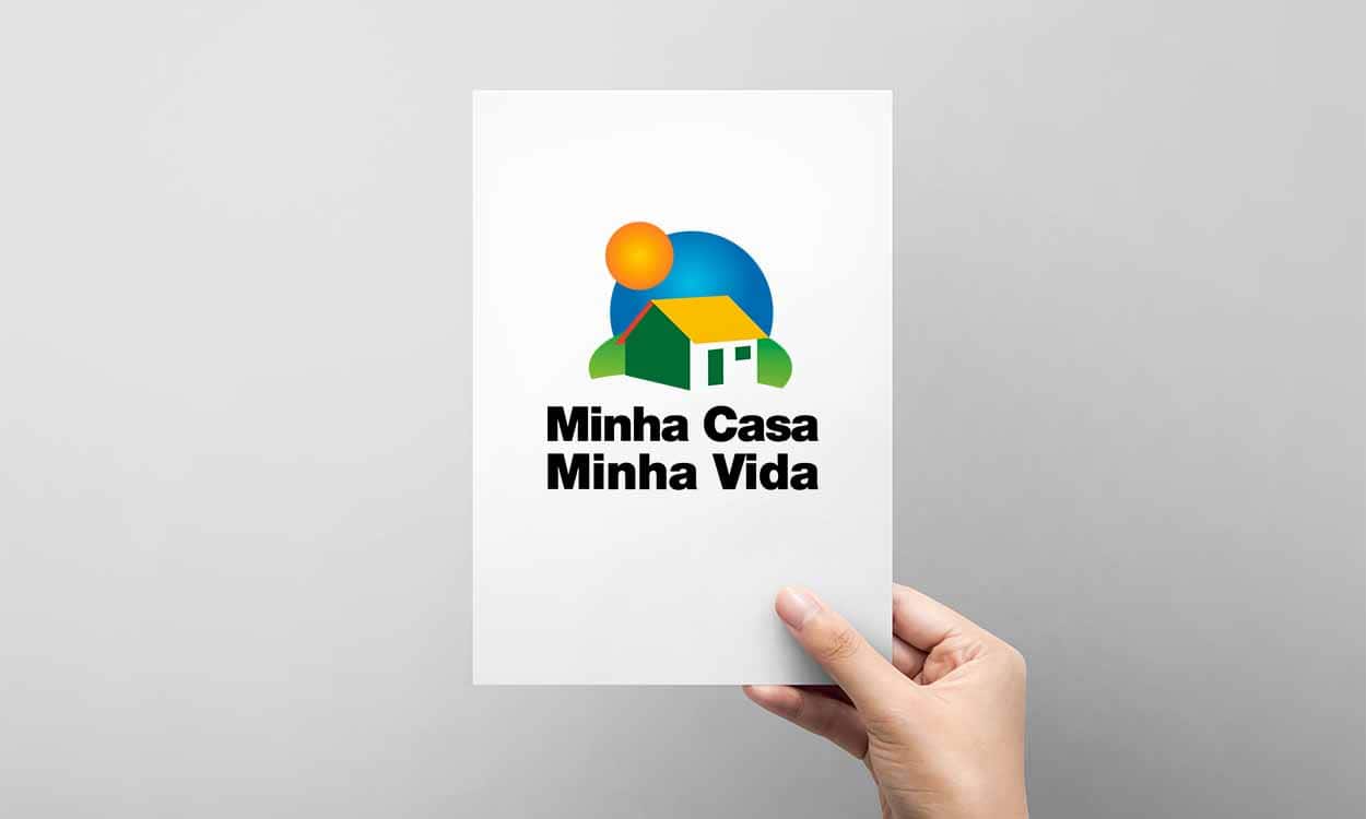 Mão segurando um papel com o logo do programa Minha Casa, Minha Vida.