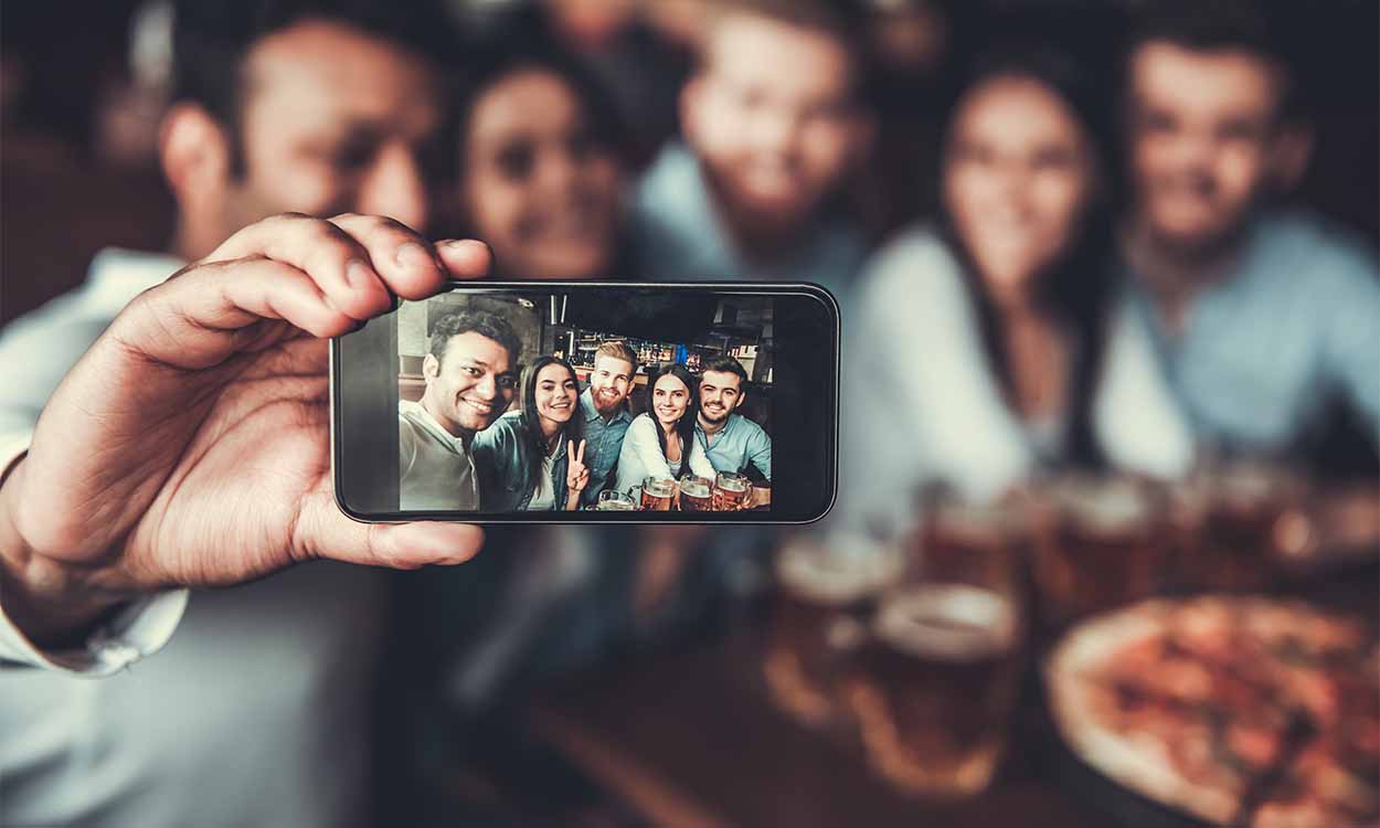 Homem tirando foto com amigos pelo celular dia do amigo