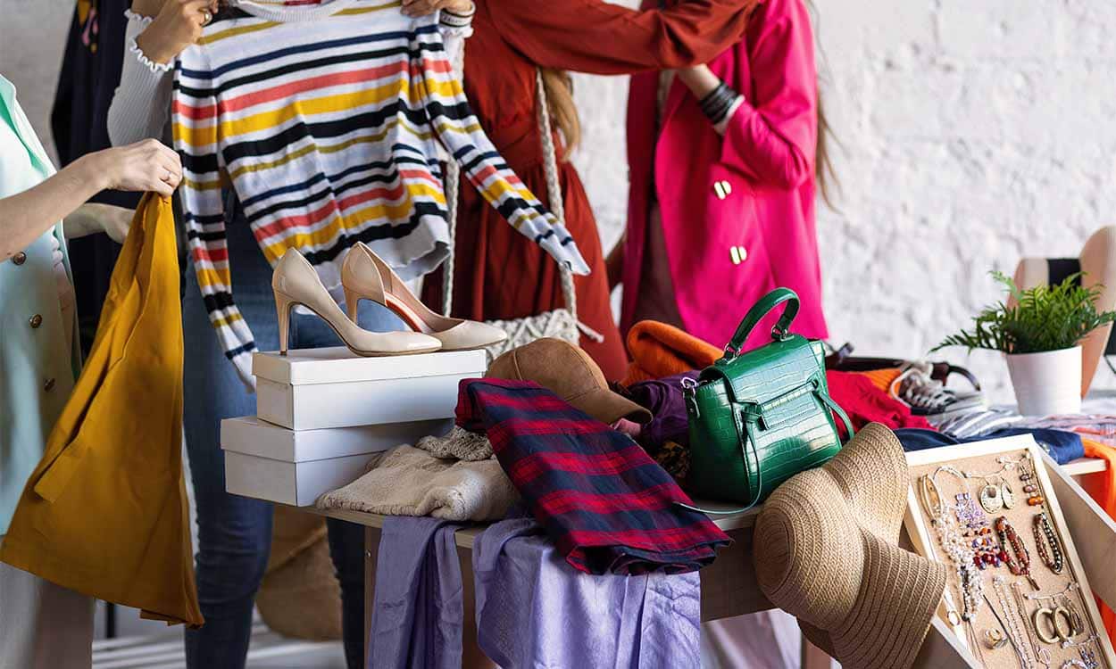 Pessoas em volta de uma mesa com roupas e calçados.