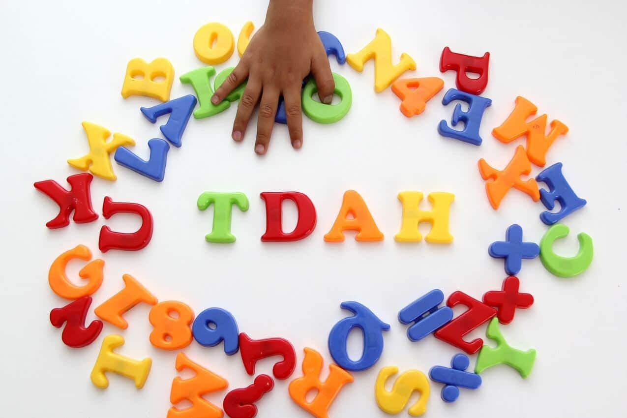 Na imagem, letras garrafais em brinquedo e mãos infantis formando a sigla TDAH