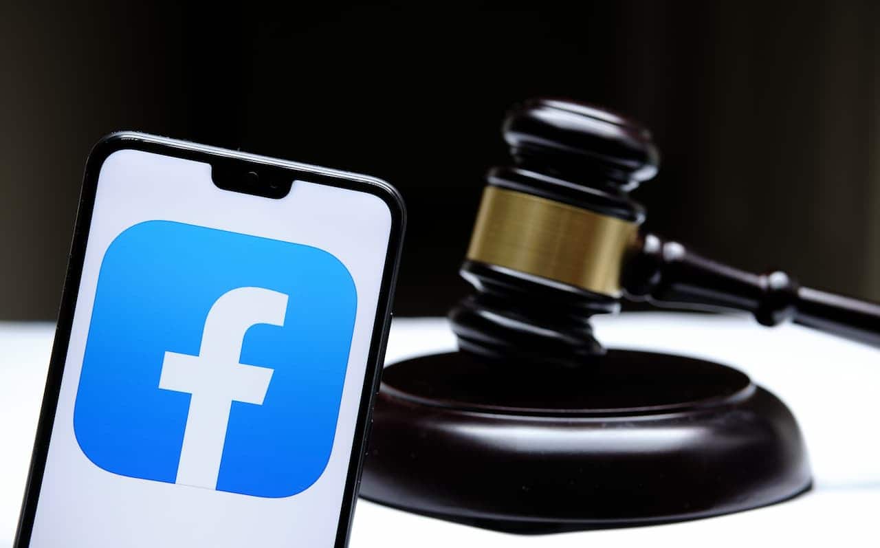 celular com logo do Facebook na tela e martelo de juiz ao lado