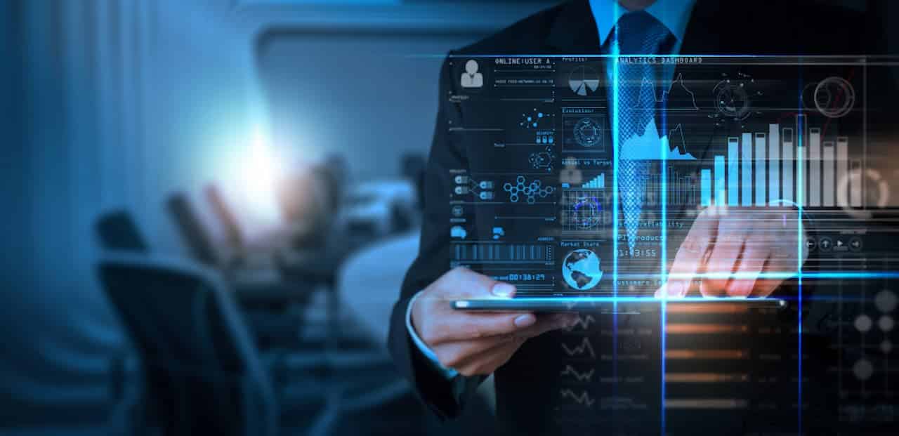 Homem de terno segurando tablet. À frente, imagem de gráficos tecnológicos.