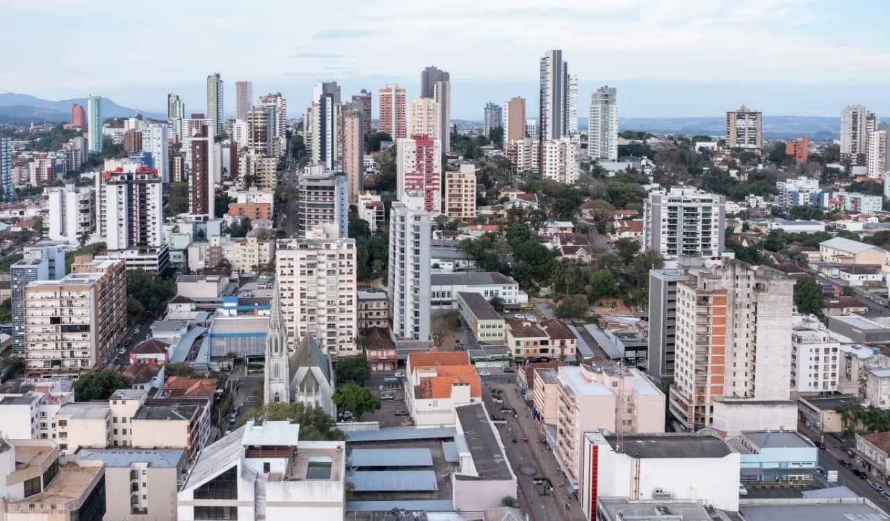 A imagem mostra uma cidade do alto. Com vários prédios e casa. déficit habitacional