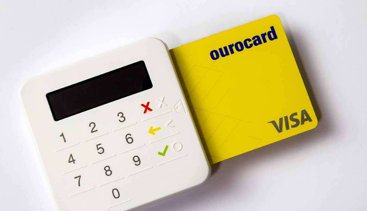 Cartão Visa Ourocard amarelo inserido em uma maquininha banco do brasil