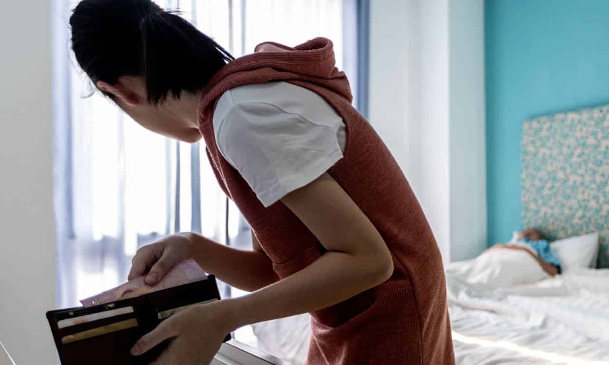 Jovem no ato de furtar dinheiro da carteira de uma pessoa que está dormindo
