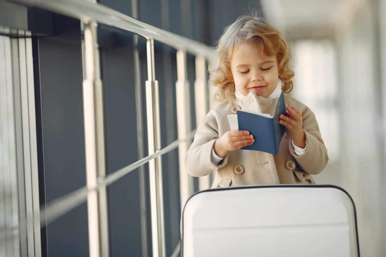 Criança segurando passaporte com mala de viagem
