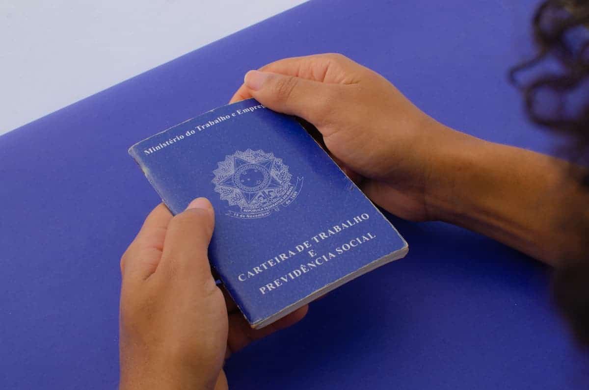 Mão segurando uma carteira de trabalho