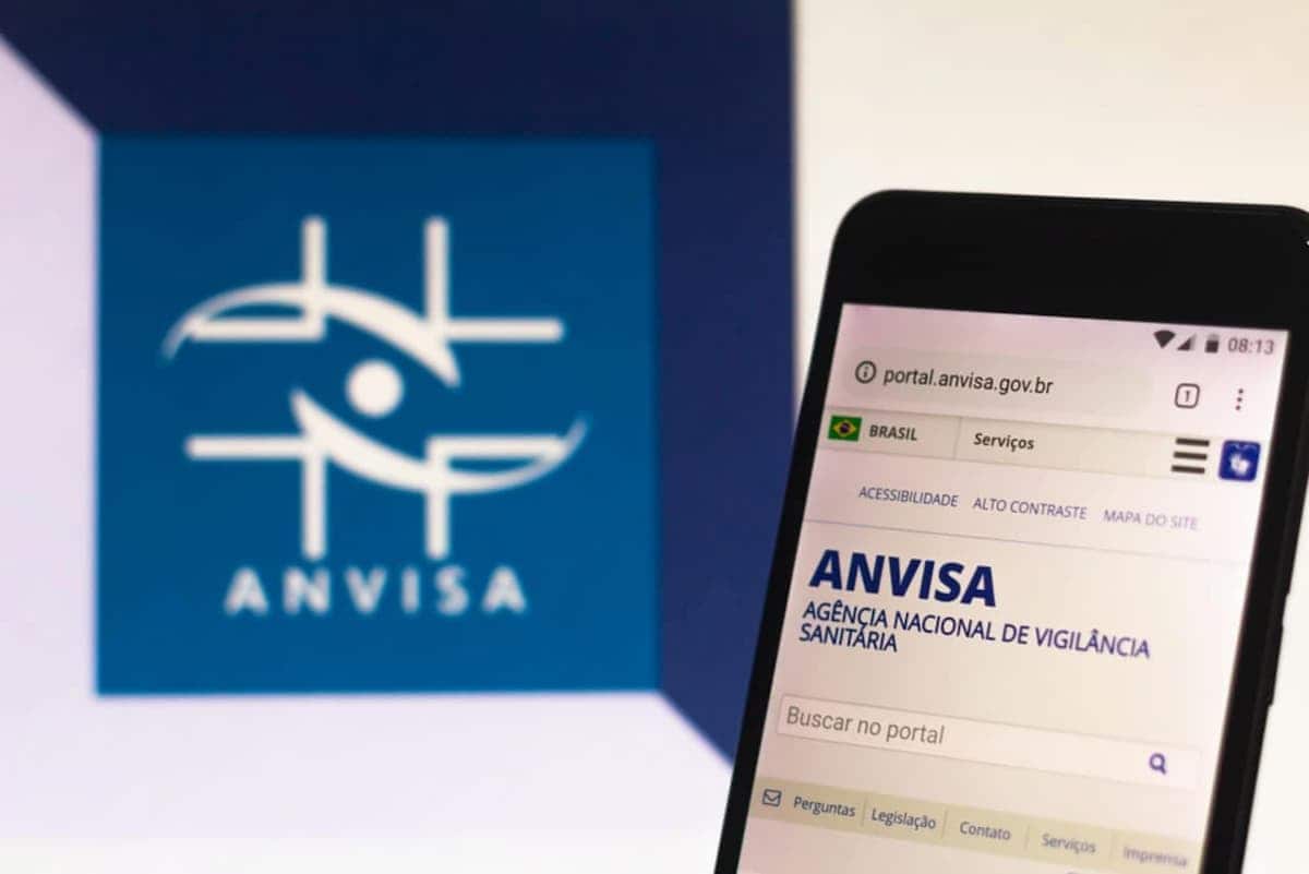 Logo Anvisa ao lado de celular com site da Anvisa aberto.