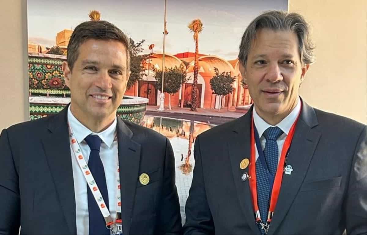 Foto do presidente do Banco Central, Roberto Campos Neto, ao lado do Ministro da Fazenda, Fernando Haddad, com prêmio nas mãos