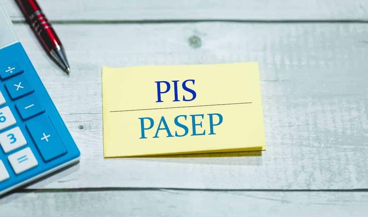 Bloco de anotações com as siglas PIS/Pasep ao lado de uma caneta e uma calculadora Caixa e BB