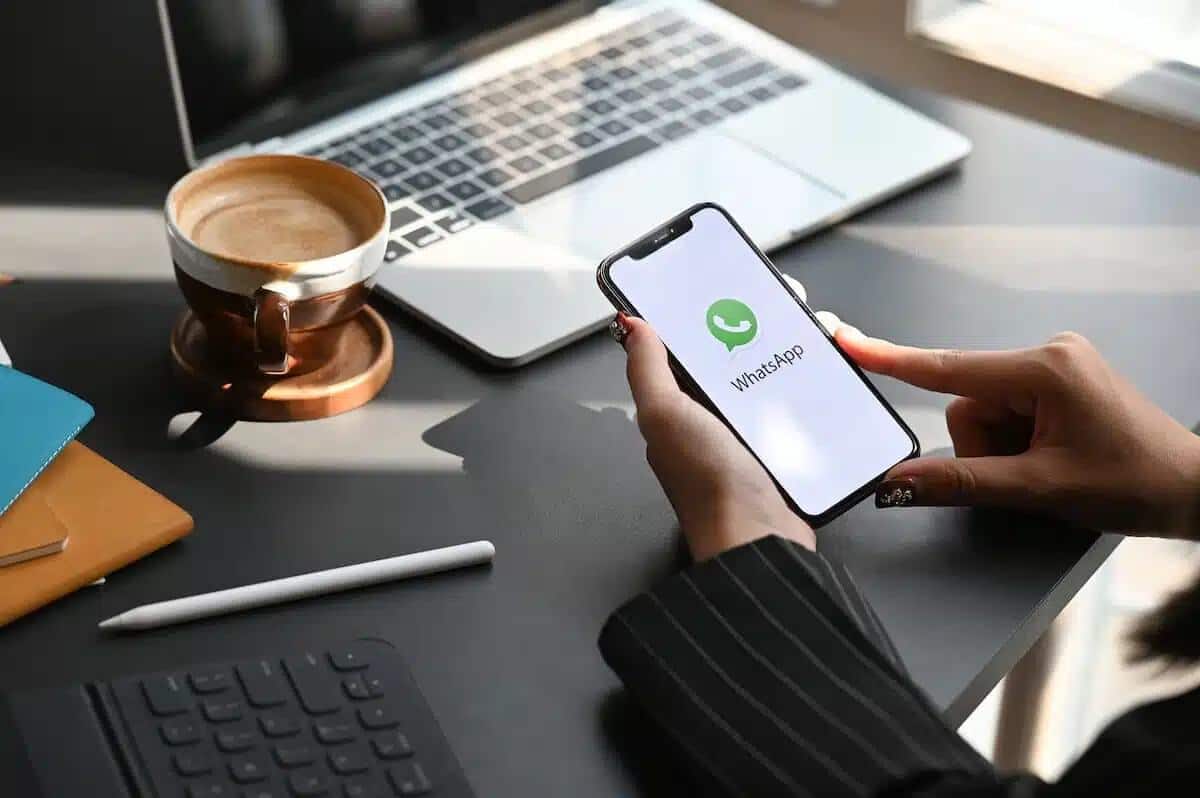 Aplicativo do Whatsapp aberto em Smartphone com usuário apoiando as mãos sobre a mesa de trabalho