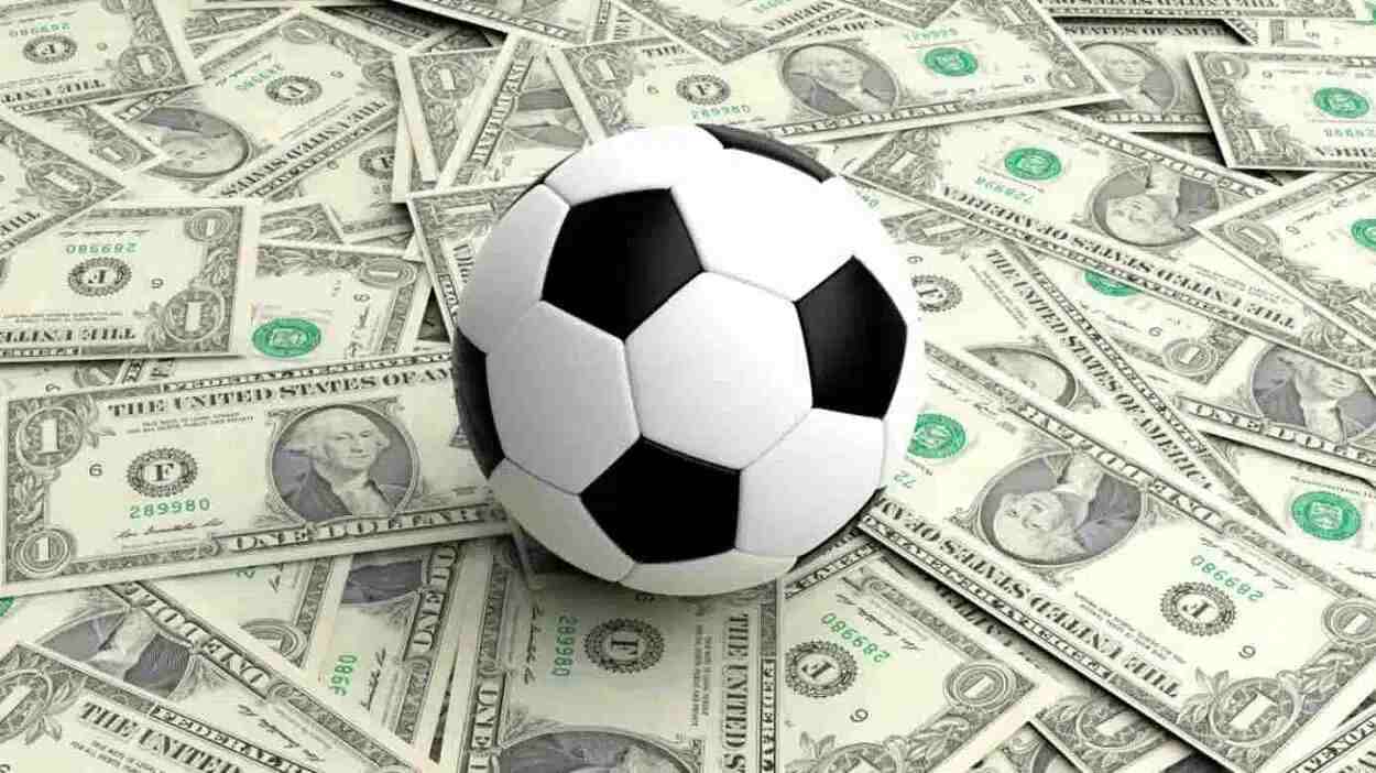 bola de futebol sobre várias cédulas de dólares.
