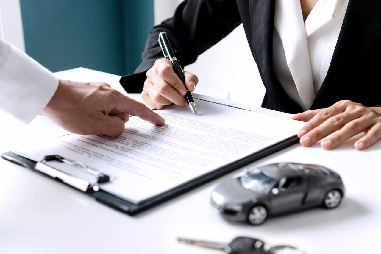 Homem assinando documento para comprar um carro. crlv