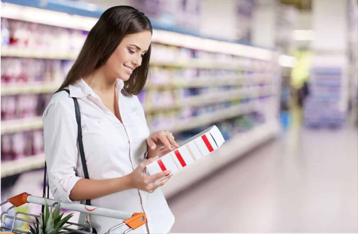 Mulher lendo embalagens de produtos no supermercado