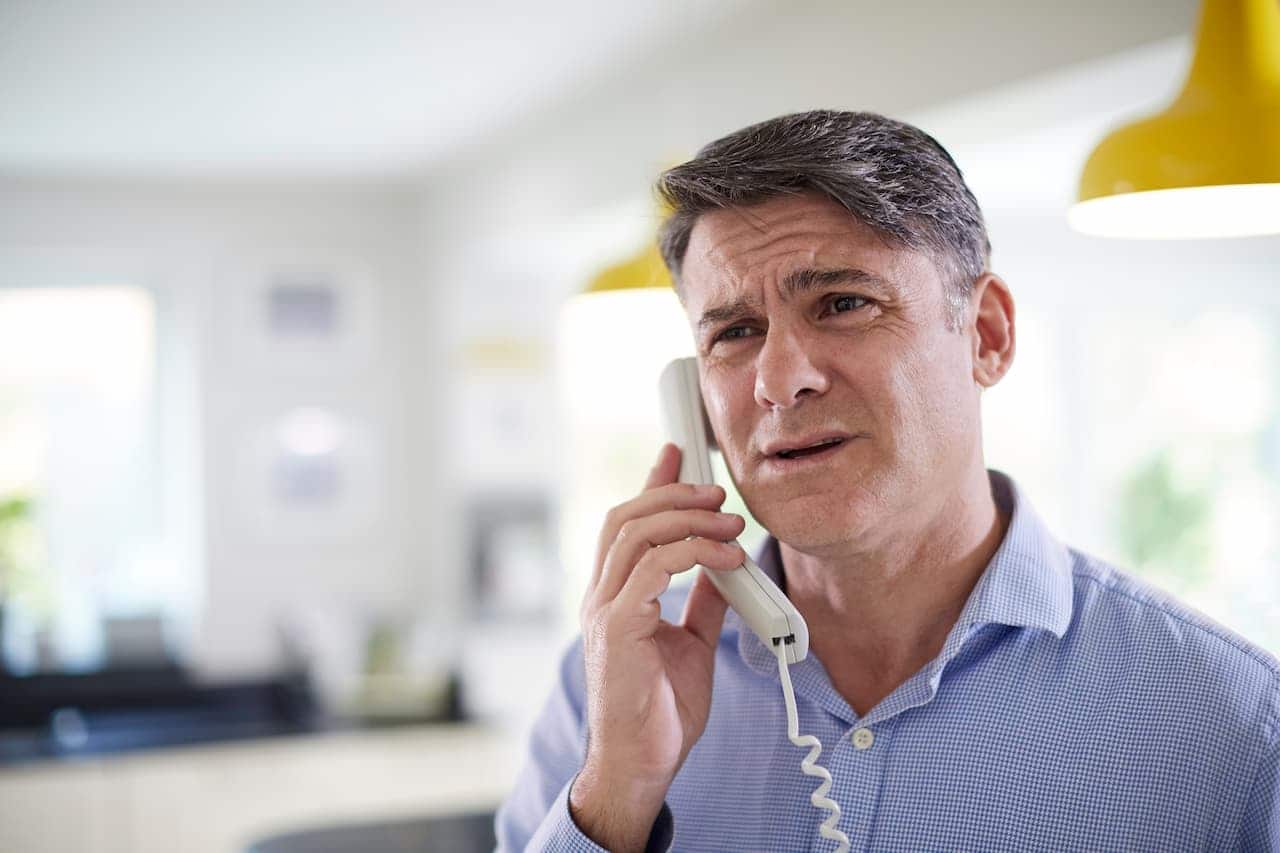 Homem branco atendendo ligação com cara de incomodado