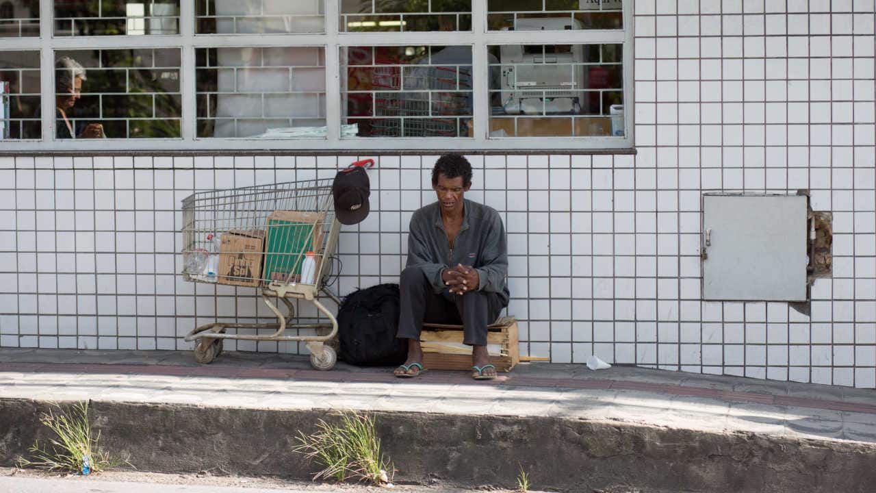 morador de rua na calçada em frente a um estabelecimento comercial