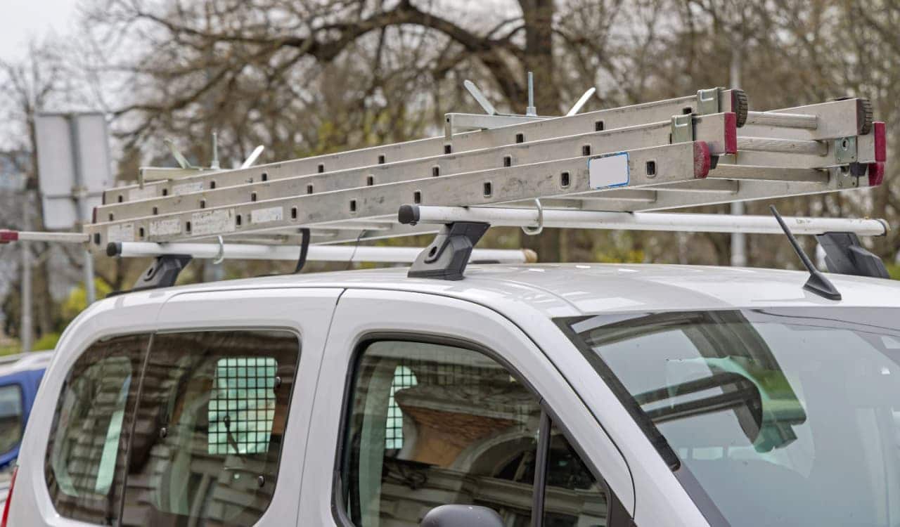 Imagem aproximada de um carro branco com uma escada anexada no teto